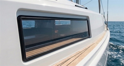 Klar støbt akrylplade monteret som bådrude på hvid sejlbåd med krystalklart udsyn til havet.